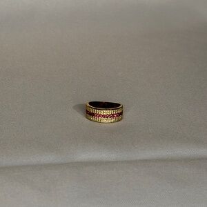 Gold tone ring with textured band and a central row of pink stones.